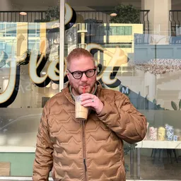 Patrick drinking a smoothie in front of a restaurant